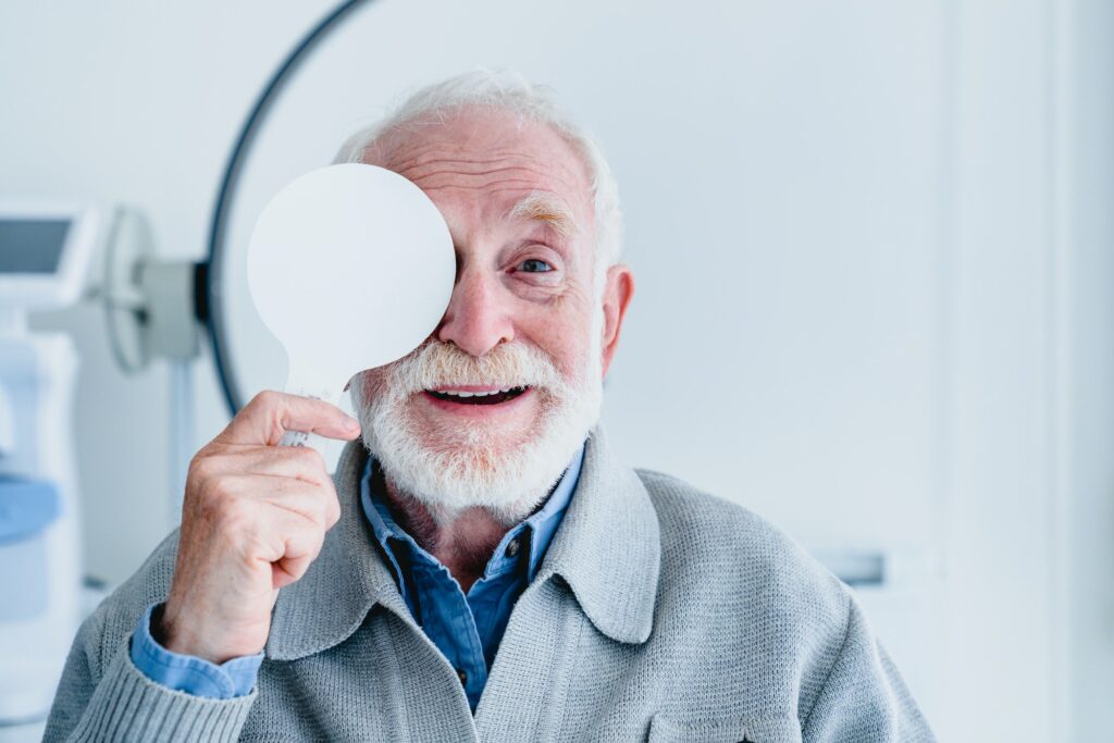 Happy aged grandfather checking up vision closing his eye