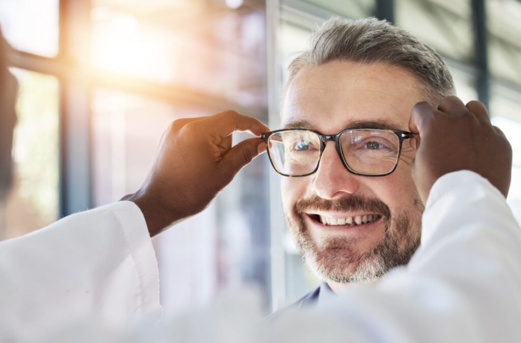 A person having their eyeglasses fitted by an optician at their optometrist's office.